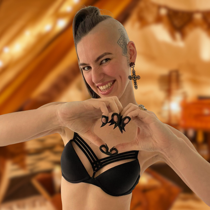 Young woman with a big smile wearing Stimming Claws for self-soothing while making a heart gesture