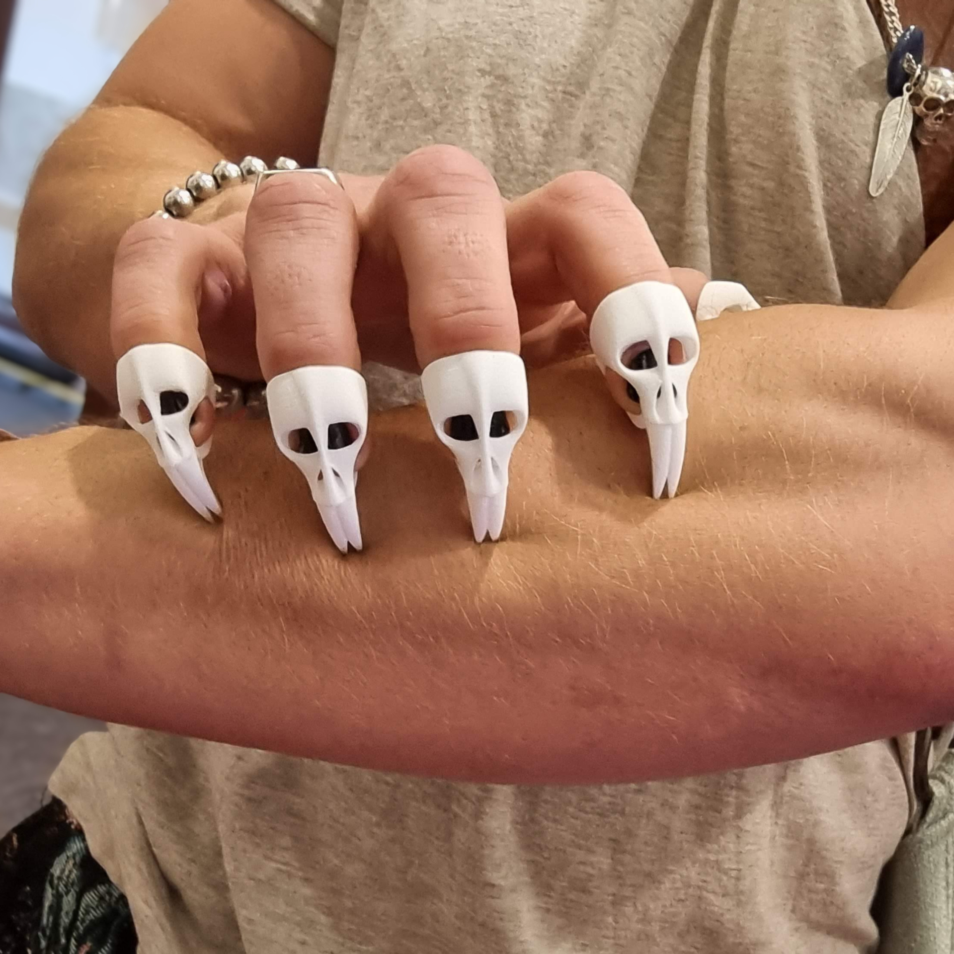 Strong fingers clasp muscular forearm with finely detailed finger claws in the shape of small skulls