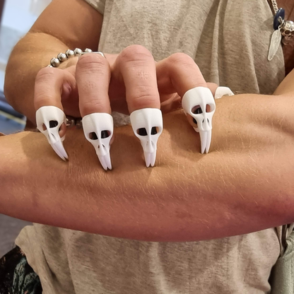 Strong fingers clasp muscular forearm with finely detailed finger claws in the shape of small skulls