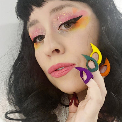 Rainbow Kitten Pride Claws worn on the fingertips — colourful nylon finger claws for sensory play — model resting the pride claws against her face with matching pride makeup