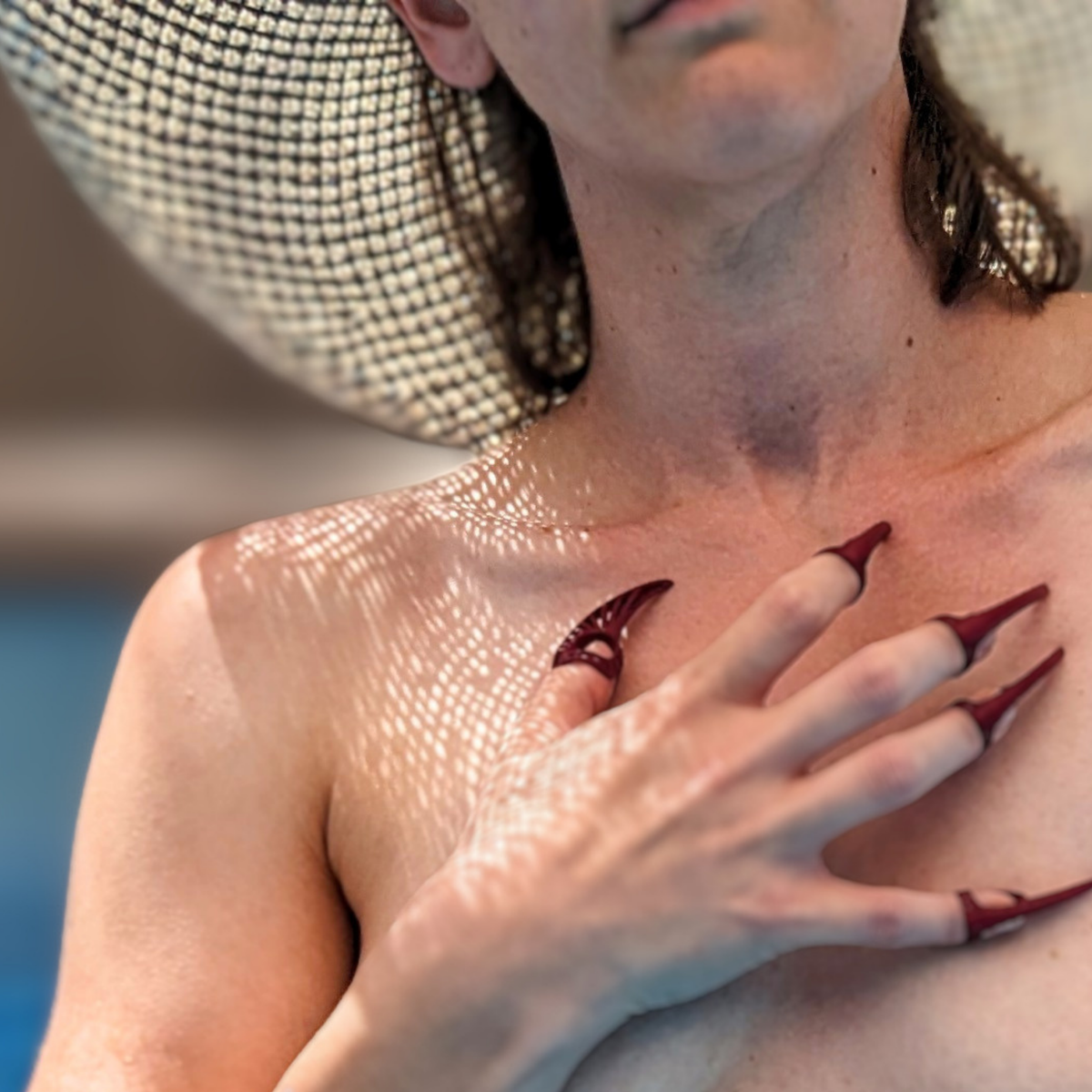 Woman in a sun hat relaxing in a pool, wearing red Steampunk Nylon Claws